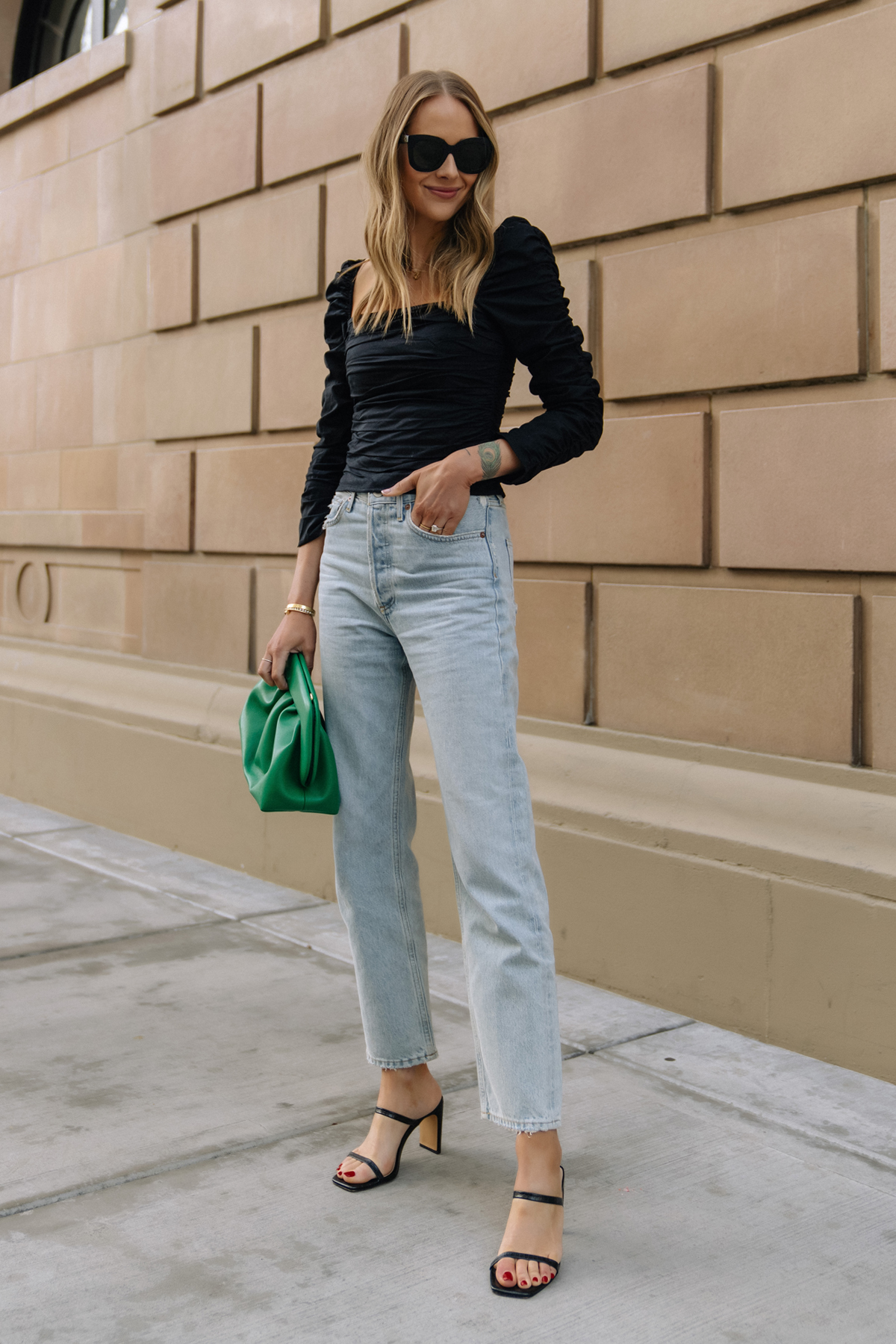 Fashion Jackson Wearing Black Rouched Reformation Top AGOLE 90s Loose Fit Jeans Black Heeled Sandals Green Clutch Spring Date Night Outfit Street Style