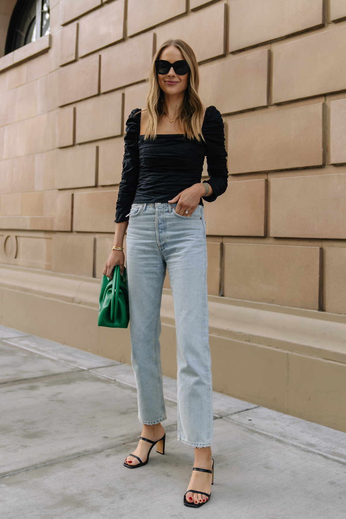 Fashion Jackson Wearing Black Rouched Reformation Top AGOLE 90s Loose Fit Jeans Black Heeled Sandals Green Clutch Spring Date Night Outfit