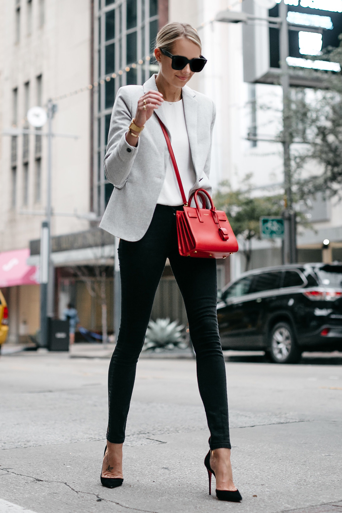 Woman in red blazer and black pants standing on gray concrete