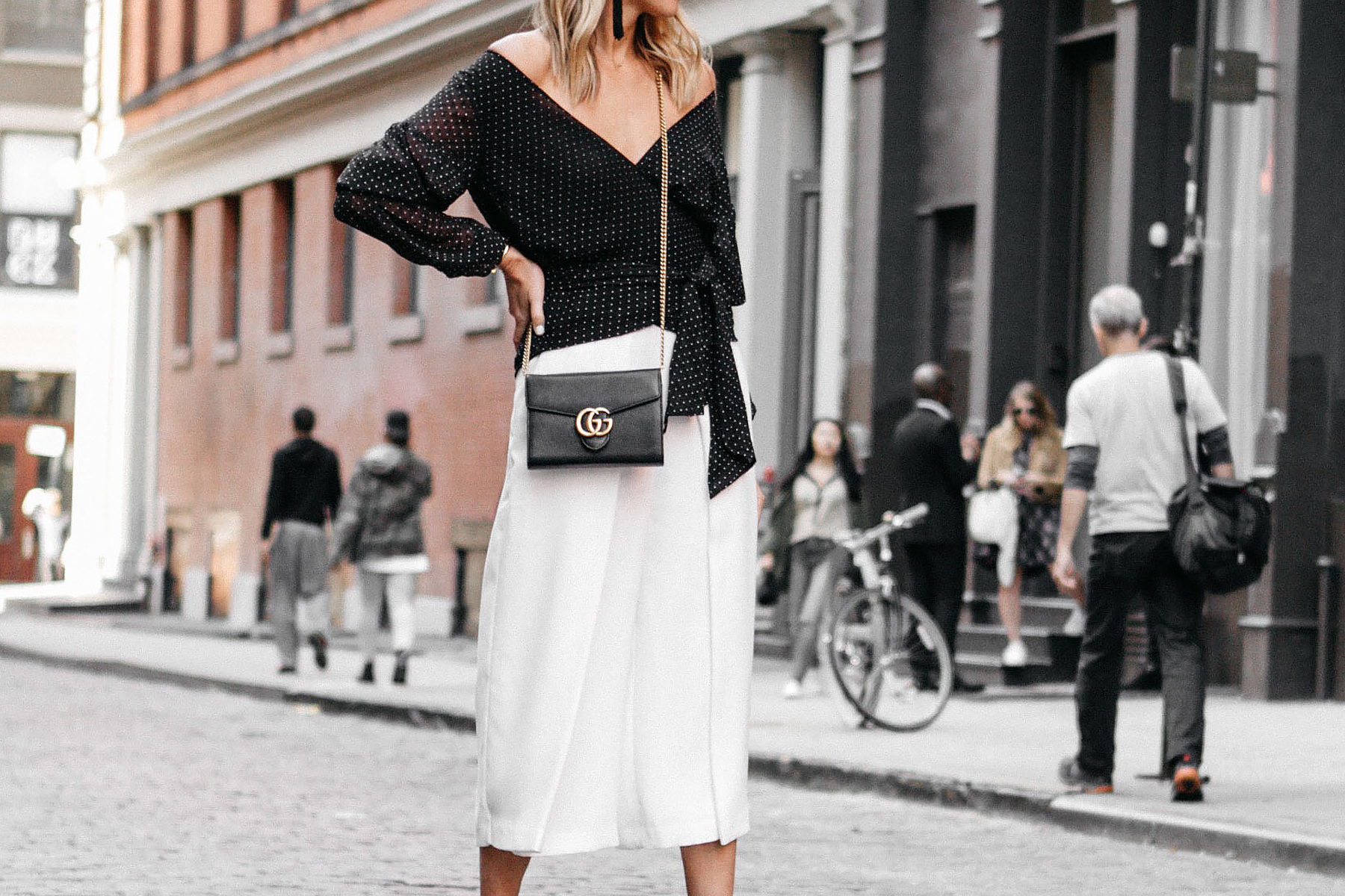 LONDON - FEBRUARY, 2017: Mid section of fashionable woman wearing a black  and white striped skirt and white batwing top holding a Hermes clutch bag  in the street during London Fashion Week