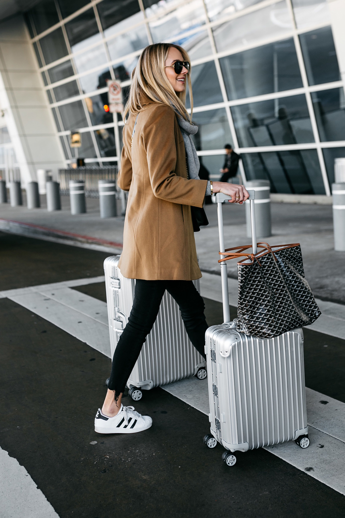 Blonde Woman Wearing Camel Coat Black Ripped Skinny Jeans adidas Superstar Sneakers Rimowa Luggage Fashion Jackson Dallas Blogger Fashion Blogger Street Style Airport Style