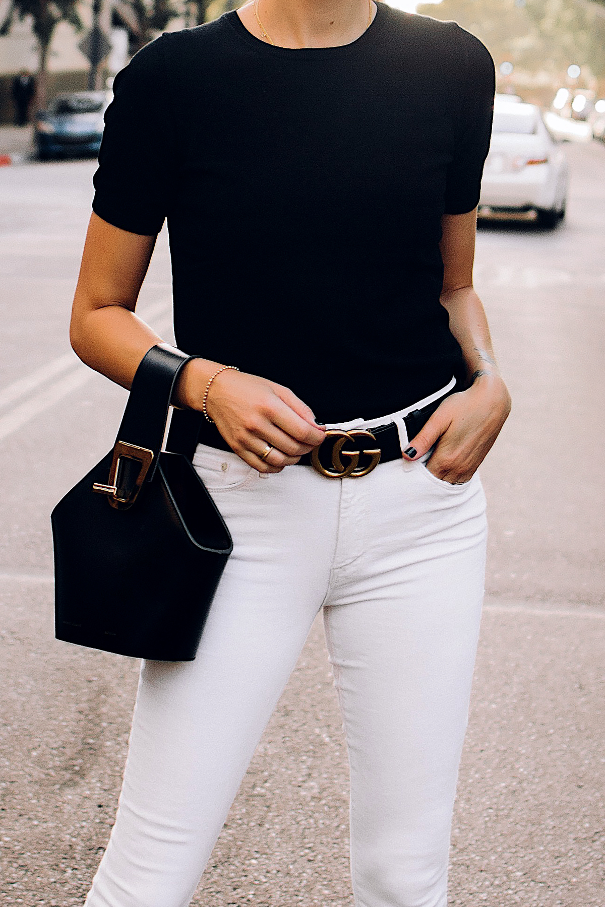 Lexica - from the right shoulder hangs a louis vuitton shopper style  handbag. the woman is wearing a white turtleneck jumper and a black skirt  with a gucci belt with the double