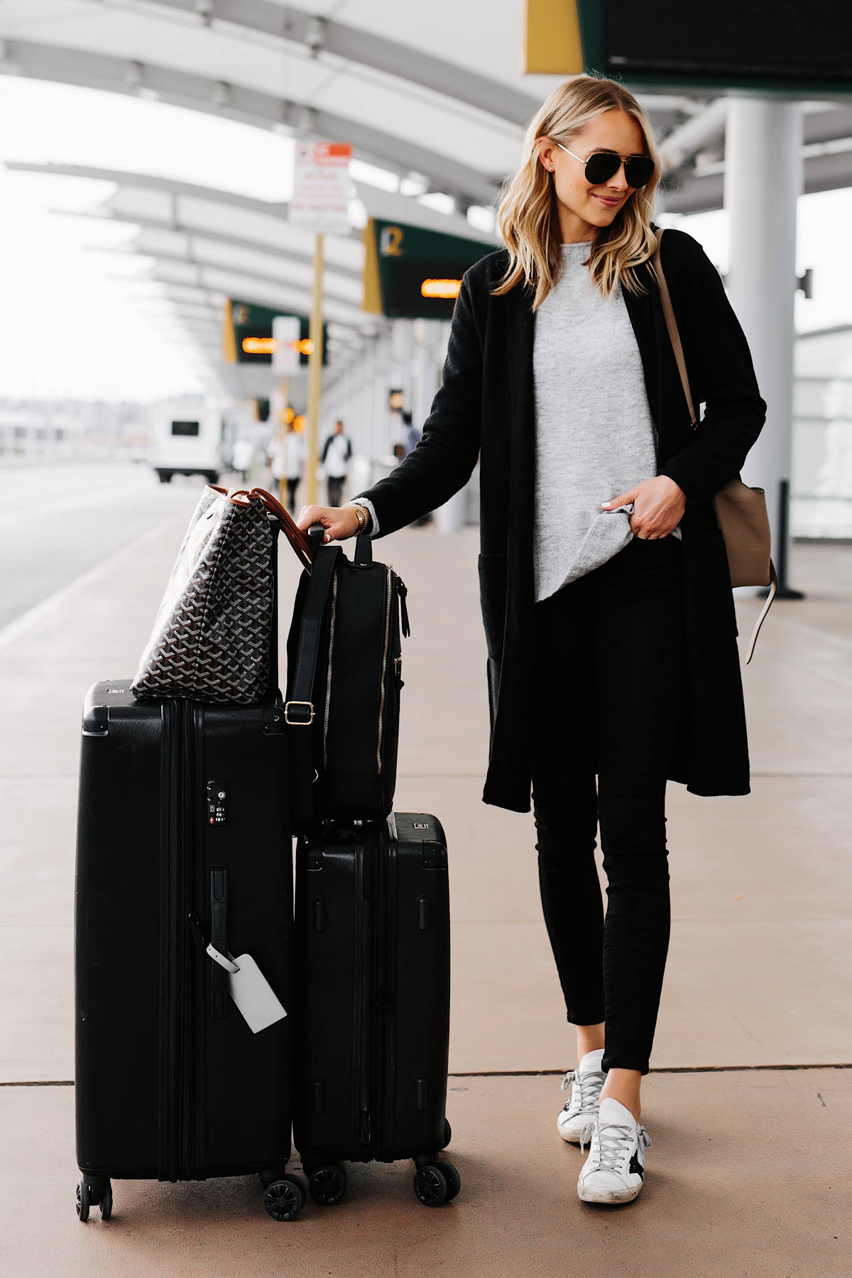 Fashion Jackson Wearing Black Coatigan Grey Sweater Black SKinny Jeans Golden Goose Sneakers Airport Outfit Calpak Black Luggage Set Goyard Tote