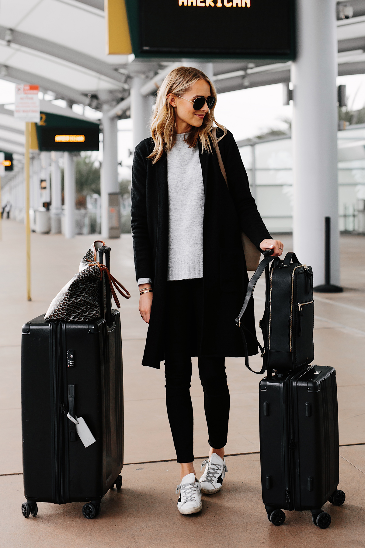 Fashion Jackson Wearing Black Coatigan Grey Sweater Black Skinny Jeans Golden Goose Sneakers Airport Outfit Calpak Black Luggage Set Goyard Tote