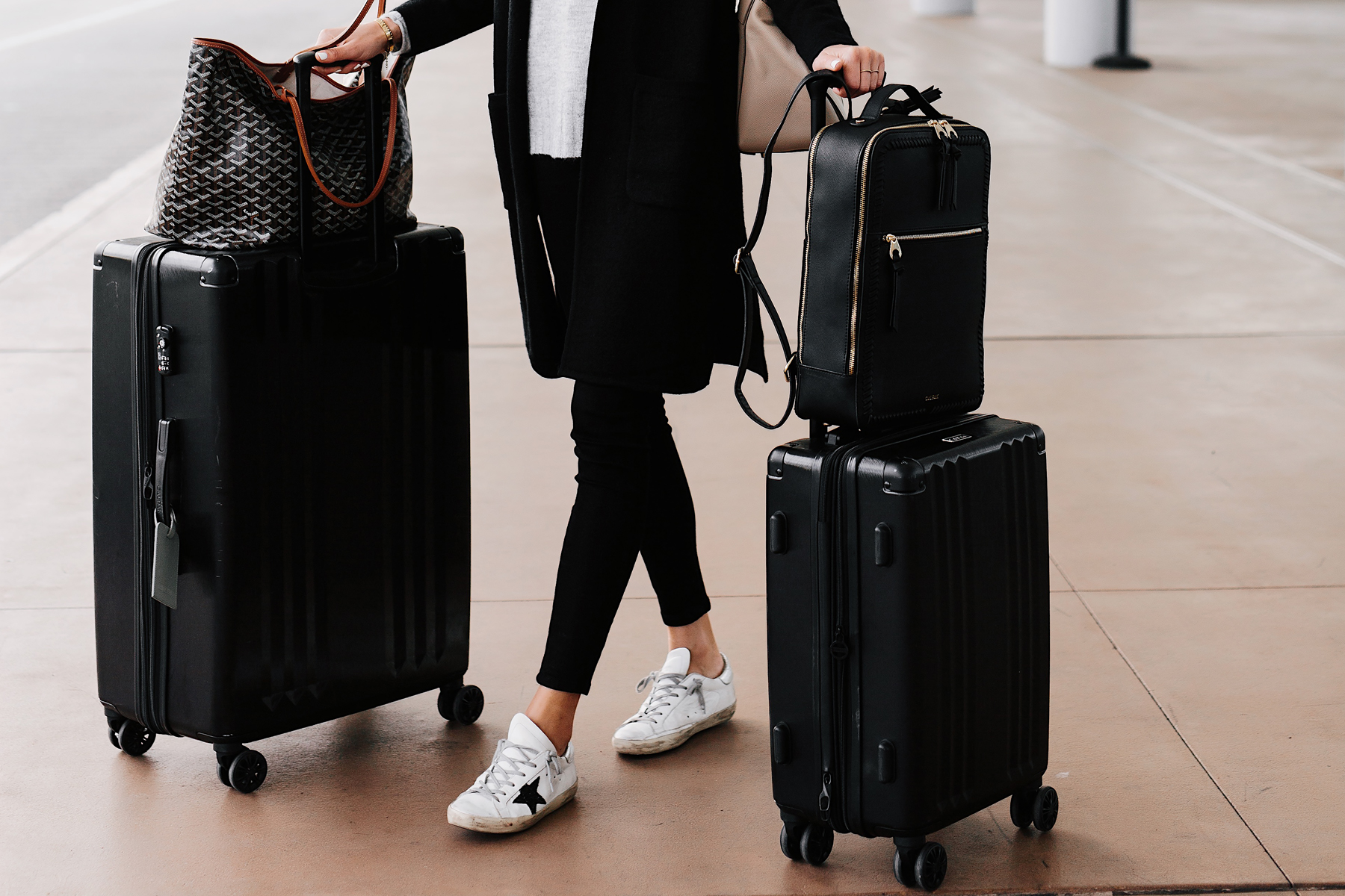 Woman at Airport with Calpak Kaya Black Backpack Calpak Black Luggage Goyard Tote Airport Style