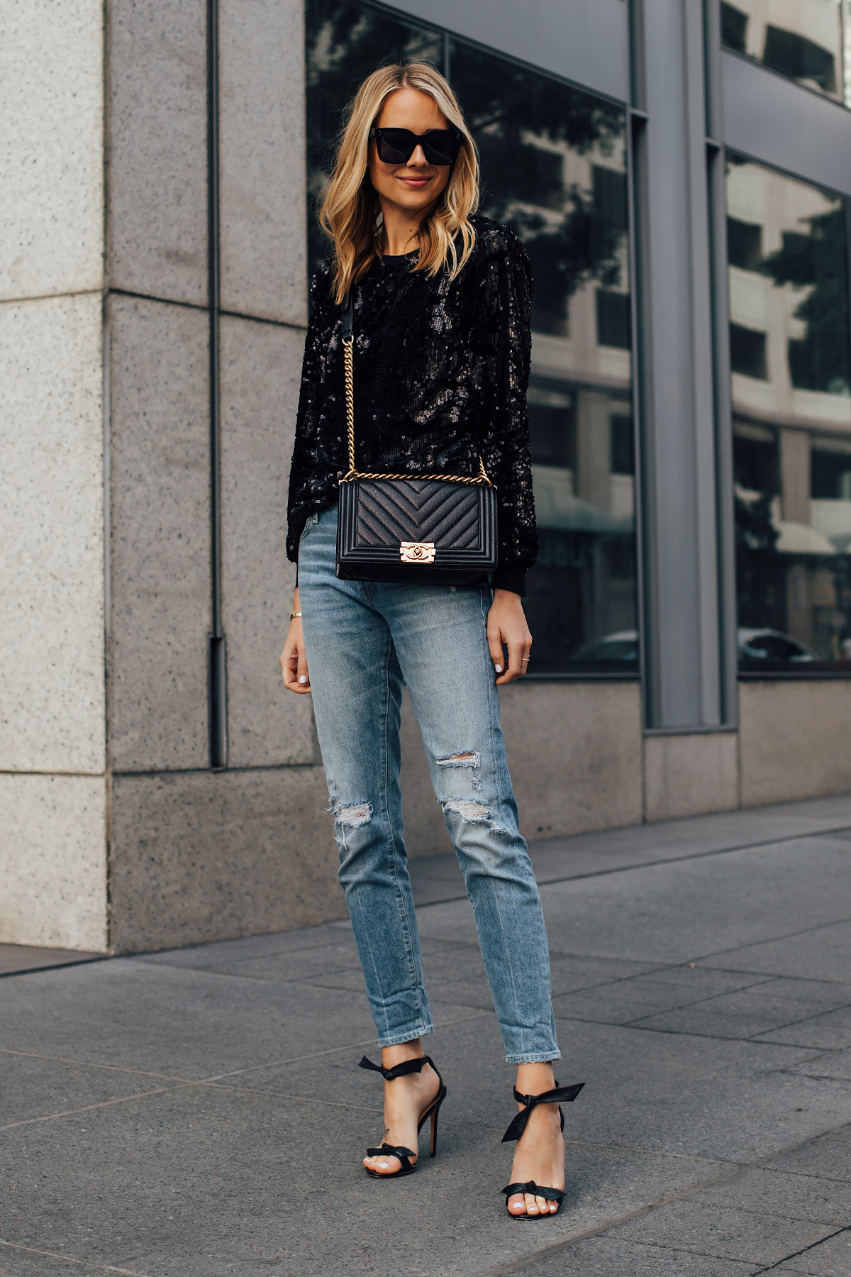 Blonde Woman Wearing Black Sequin Top Ripped Skinny Jeans Chanel Black Boy Bag Black Ankle Tie Heeled Sandals Fashion Jackson San Diego Fashion Blogger Street Style NYE Outfit