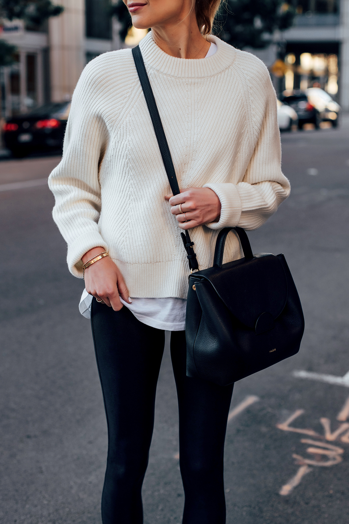 Trendy woman in an oversized grey sweater and black leather leggings