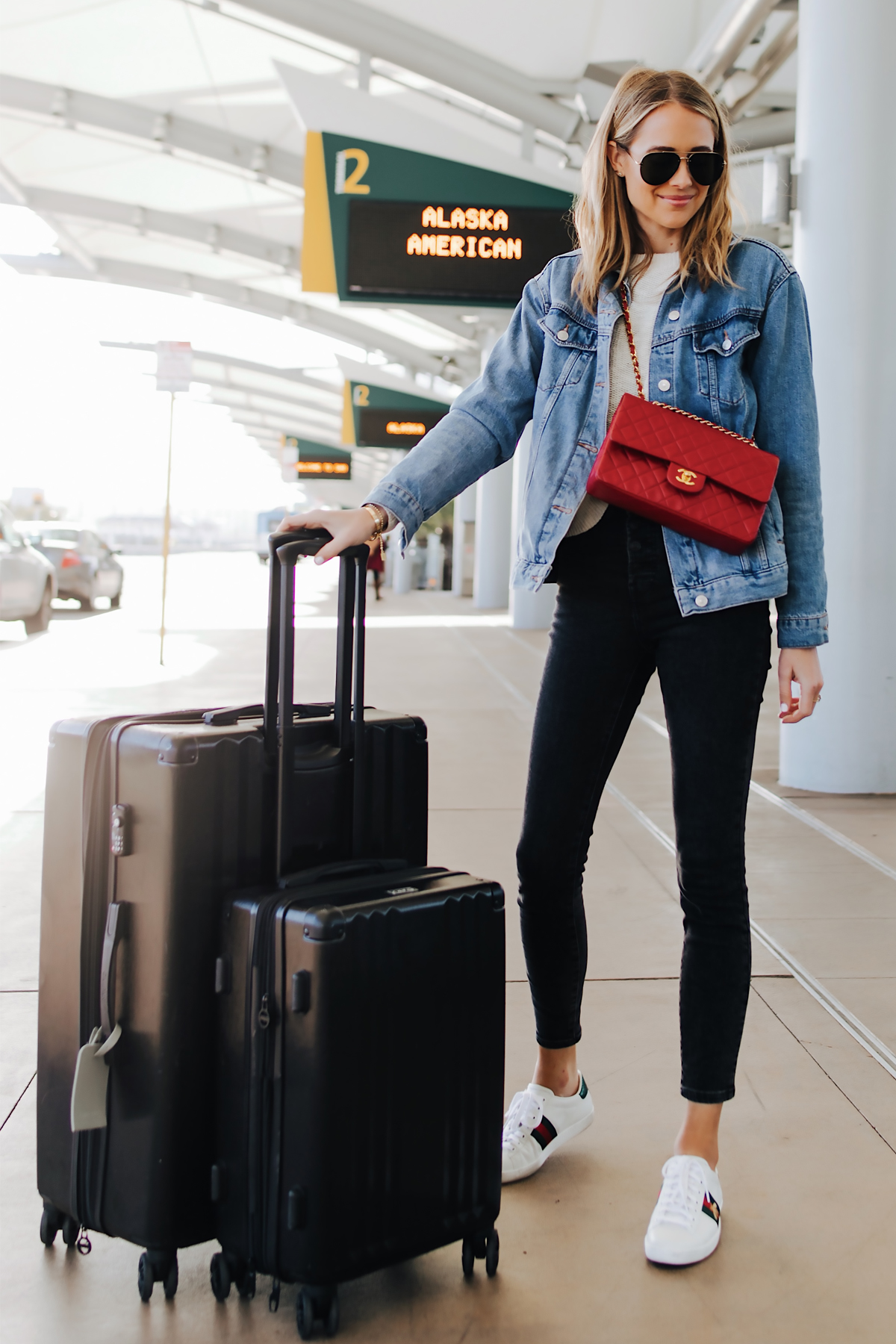 Fashion Jackson Airport Style Wearing Denim Jacket Black Skinny Jeans Gucci Sneakers Red Chanel Handbag Calpak Black Ambeur Spinner Luggage Set