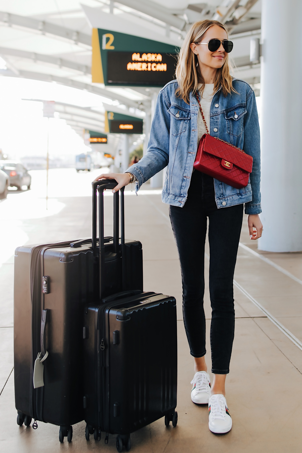 Fashion Jackson Airport Style Wearing Denim Jacket Black Skinny Jeans Gucci Sneakers Red Chanel Handbag Calpak Black Ambeur Spinner Luggage Set