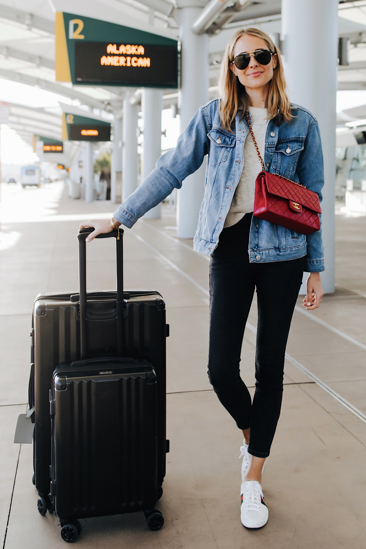 Fashion Jackson Airport Style Wearing Denim Jacket Black Skinny Jeans Gucci Sneakers Red Chanel Handbag Calpak Black Ambeur Spinner Luggage Set