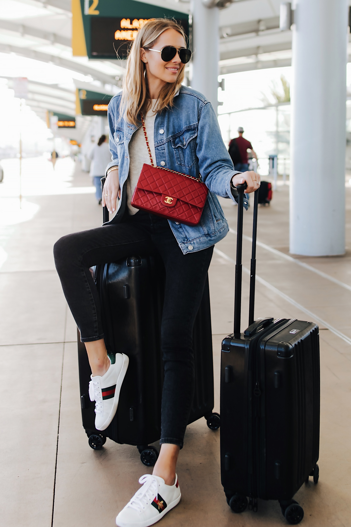 Fashion Jackson Airport Style Wearing Denim Jacket Black Skinny Jeans Gucci Sneakers Red Chanel Handbag Calpak Black Ambeur Spinner Luggage Set
