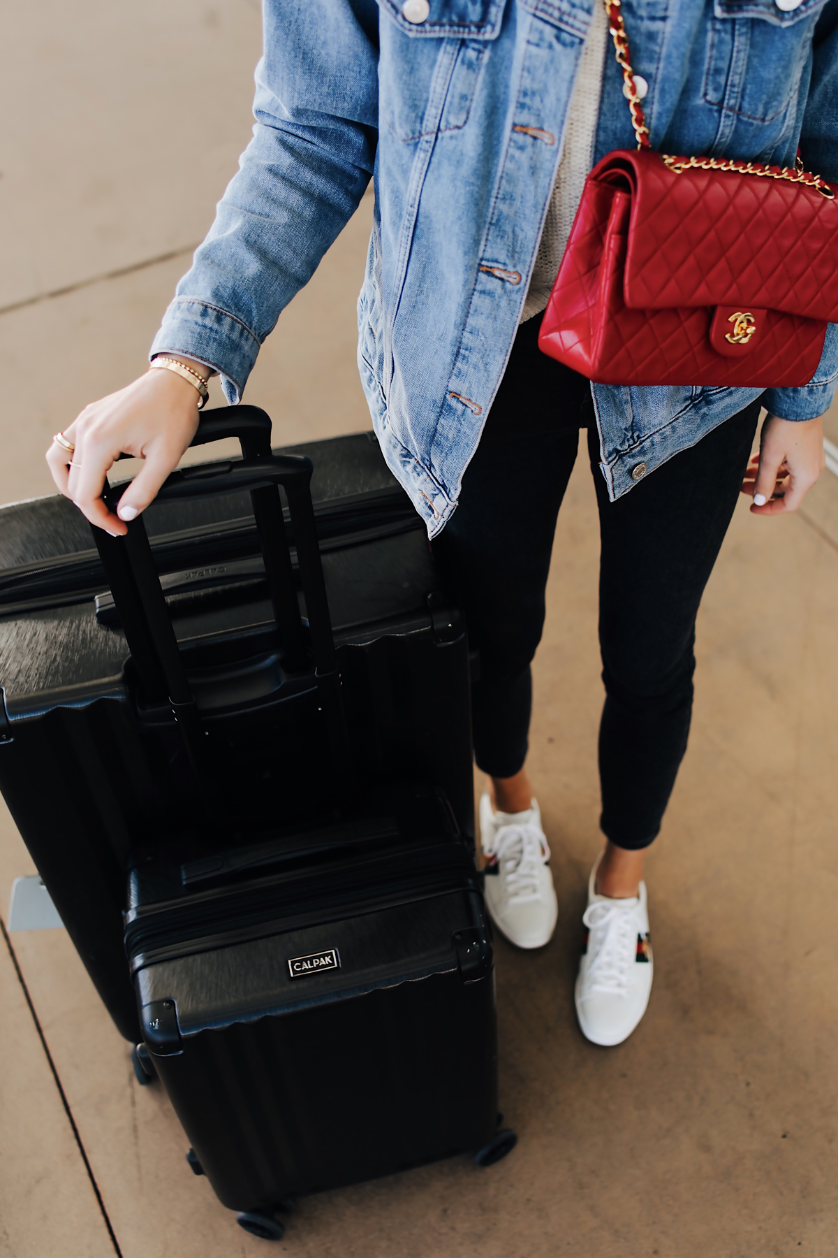 Fashion Jackson Airport Style Wearing Denim Jacket Black Skinny Jeans Gucci Sneakers Red Chanel Handbag Calpak Black Ambeur Spinner Luggage Set