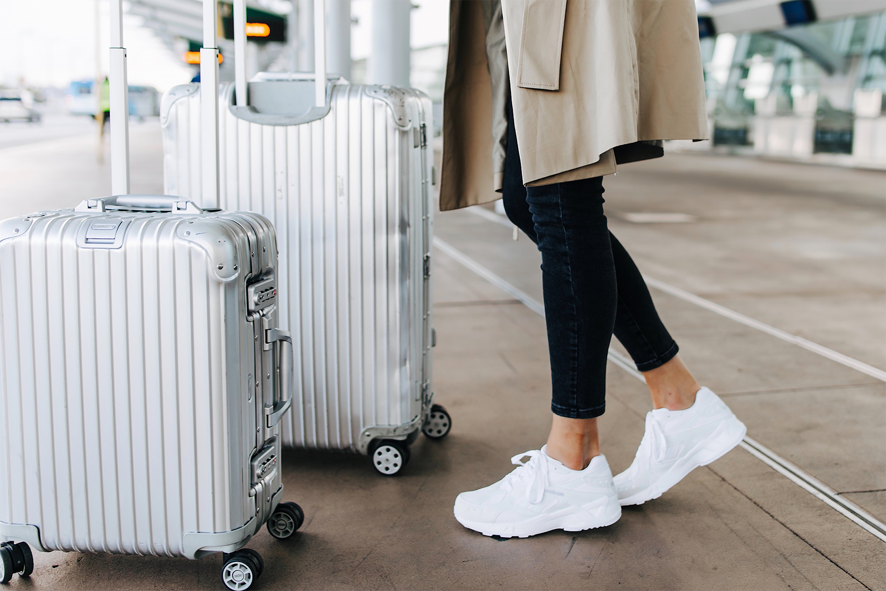 Woman Wearing Airport Travel Outfit Black Skinny Jeans Reebok Aztrek White Sneakers Rimowa Luggage Fashion Jackson San Diego Fashion Blogger Street Style