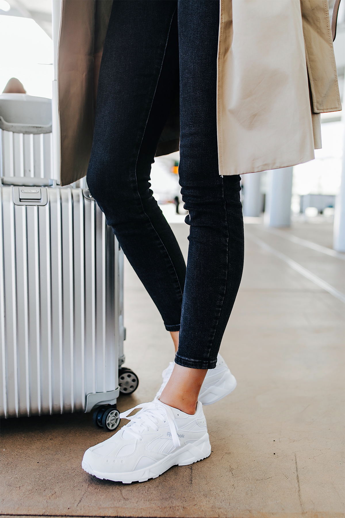 Woman Wearing Airport Travel Outfit Black Skinny Jeans Reebok Aztrek White Sneakers Rimowa Luggage Fashion Jackson San Diego Fashion Blogger Street Style