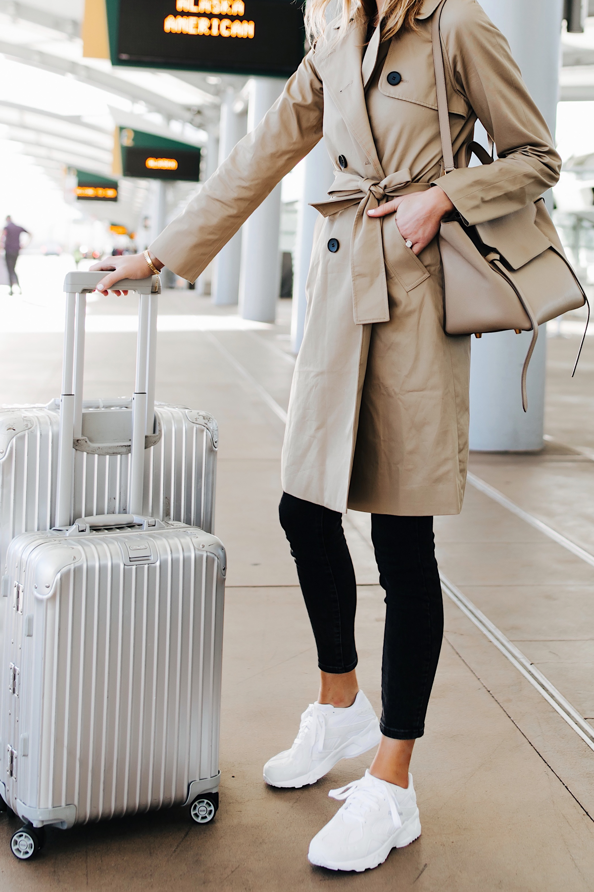 Woman Wearing Airport Travel Outfit Trench Coat Black Skinny Jeans Reebok Aztrek White Sneakers Rimowa Luggage Fashion Jackson San Diego Fashion Blogger Street Style