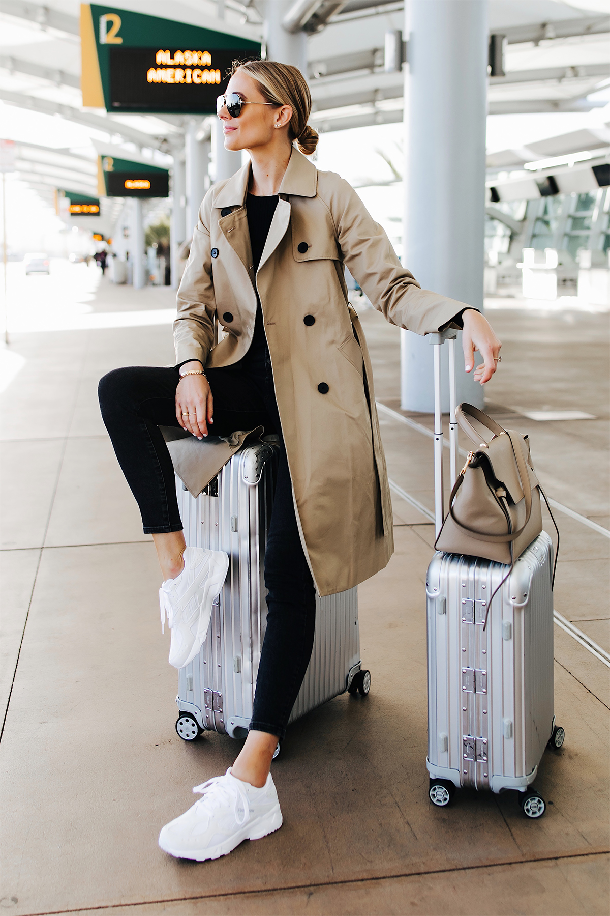 Blonde Woman Wearing Airport Travel Outfit Trench Coat Black Skinny Jeans Reebok Aztrek White Sneakers Rimowa Luggage Fashion Jackson San Diego Fashion Blogger Street Style