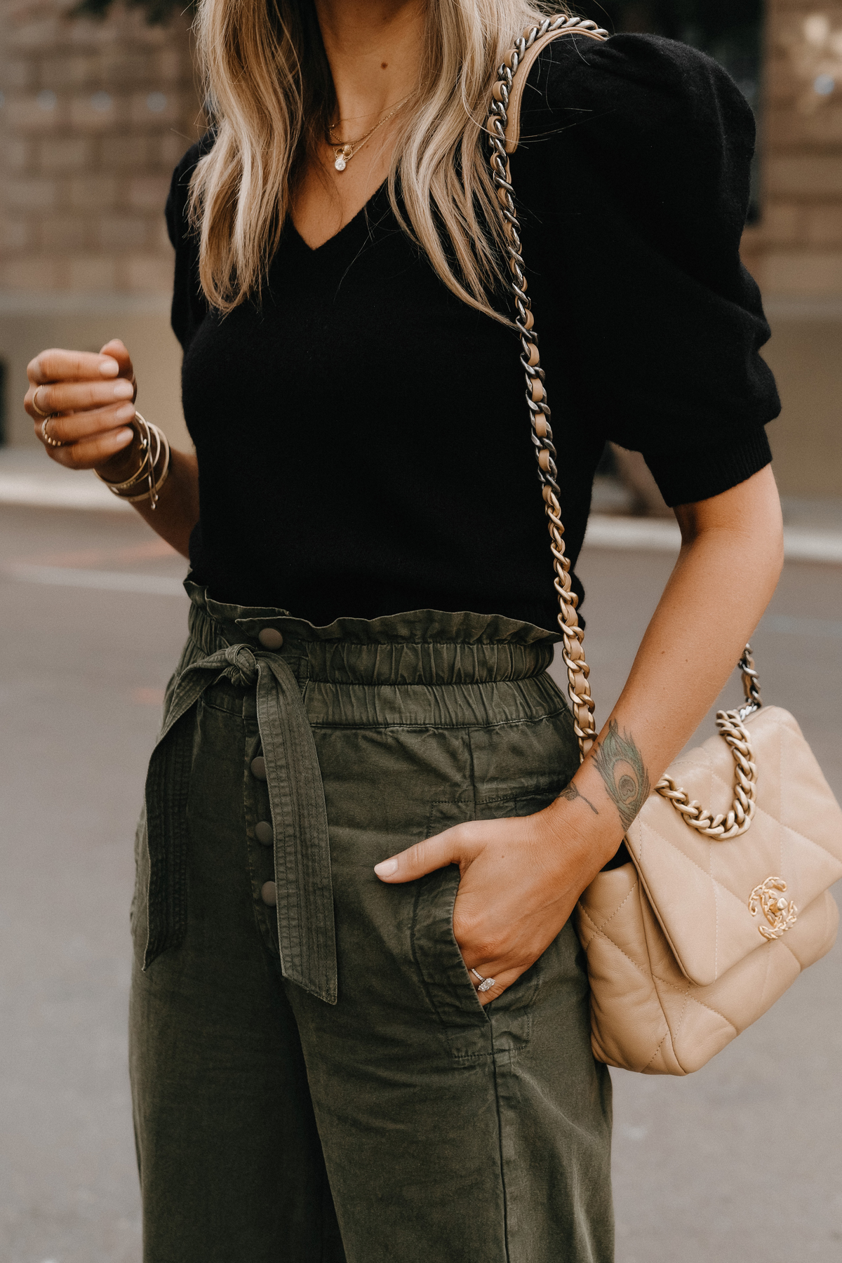 https://fashionjackson.com/wp-content/uploads/2019/06/Fashion-Jackson-Wearing-Black-Puff-Sleeve-Sweater-Olive-Green-Trousers-Chanel-19-Beige-Handbag-1.jpg