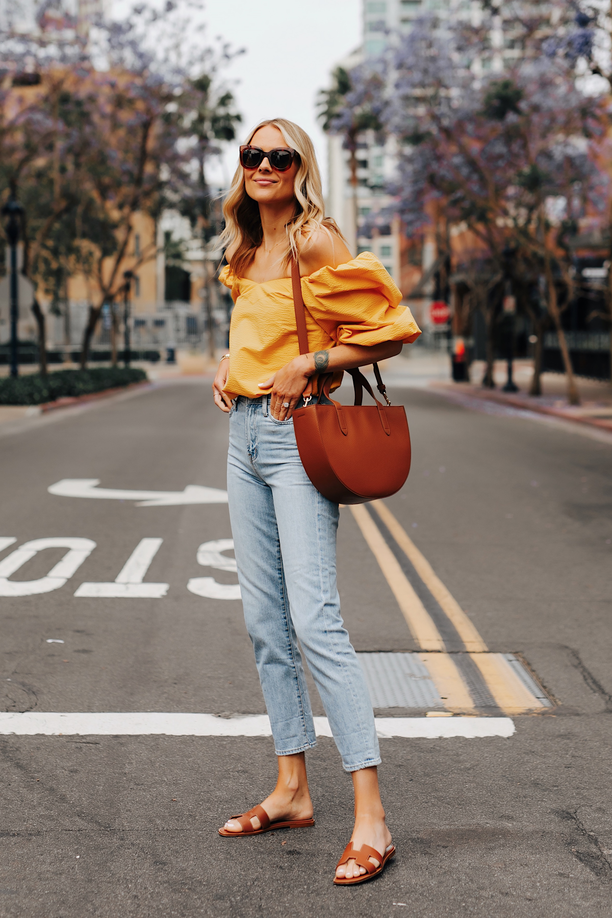 Fashion Jackson Wearing Cuyana Yellow Off the Shoulder Blouse Denim Ankle Jeans Hermes Oran Gold Sandals Cuyana Tan Semi Circle Handbag