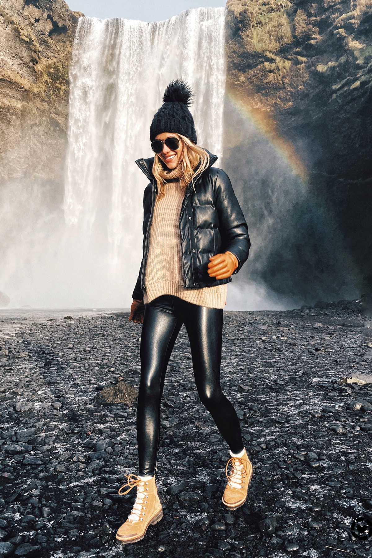 Fashion Jackson Wearing Black Puffer Jacket Black Faux Leather Leggings Winter Boots Black Beanie Outfit Skogafoss Waterfall Iceland Itinerary