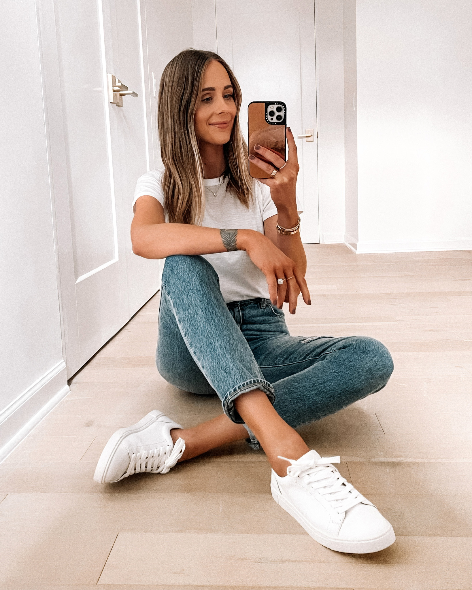 Girl wearing ripped jeans, sling bag, white tees, sneakers