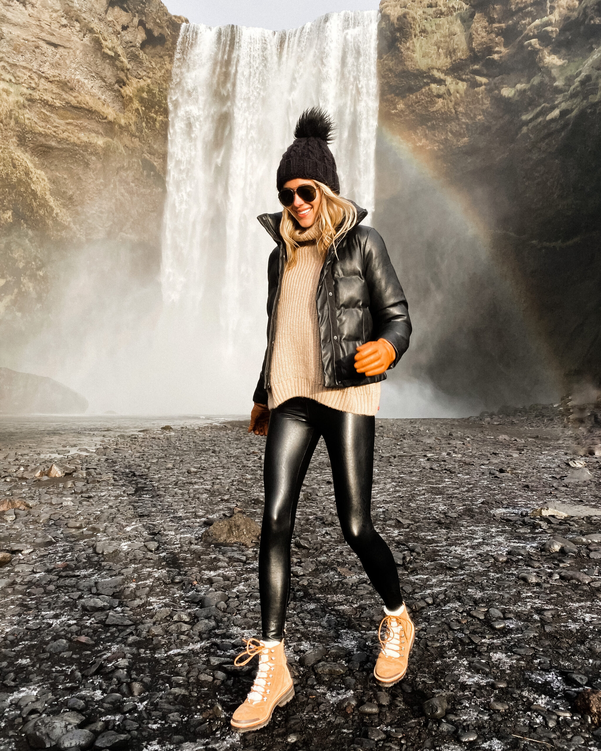 Fashion Jackson Wearing Black Puffer Jacket Black Faux Leather Leggings Winter Boots Black Beanie Outfit Skogafoss Waterfall Iceland Itinerary