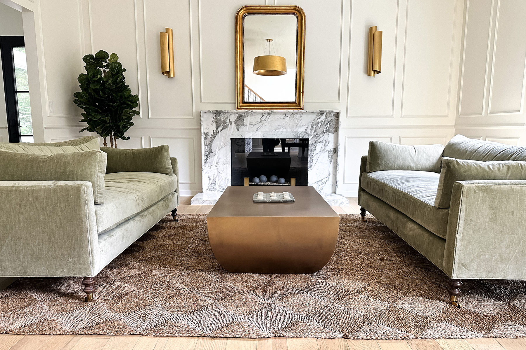 Fashion Jackson Formal Living Room Transitional Home Decor Marble Fireplace Green Velvet Couches Jute Rug Fiddle Leaf Fig Tree Louis Philippe Gilt Wall Mirror Brass Coffee Table Aerin Iva Sconces Gold Halo Pendant